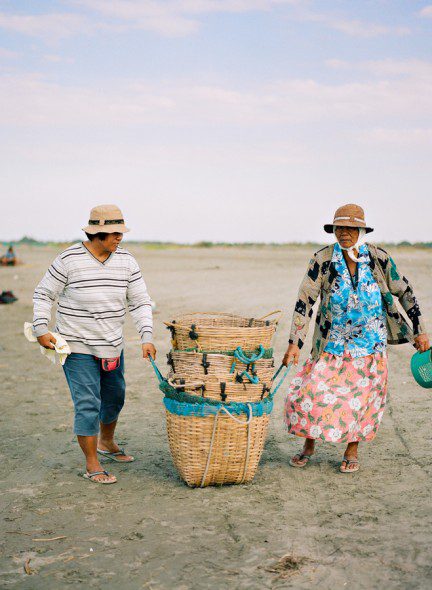 Bunn Salarzon - two old women carrying basket of fish on the beach
